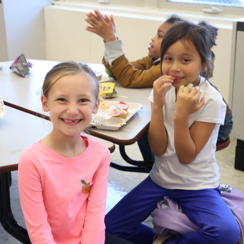 two girls sitting at a table smilng