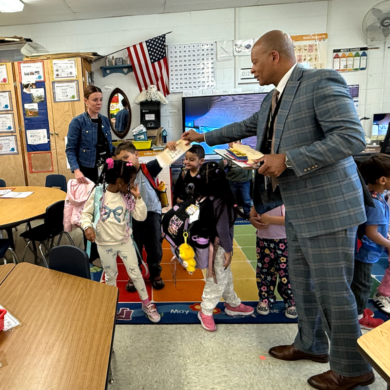 man walking handing out yellow cards in classroom