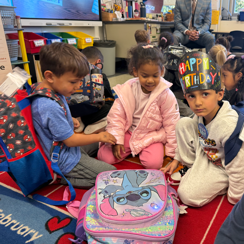 students sitting on a floor with a pink coat and blue shirt