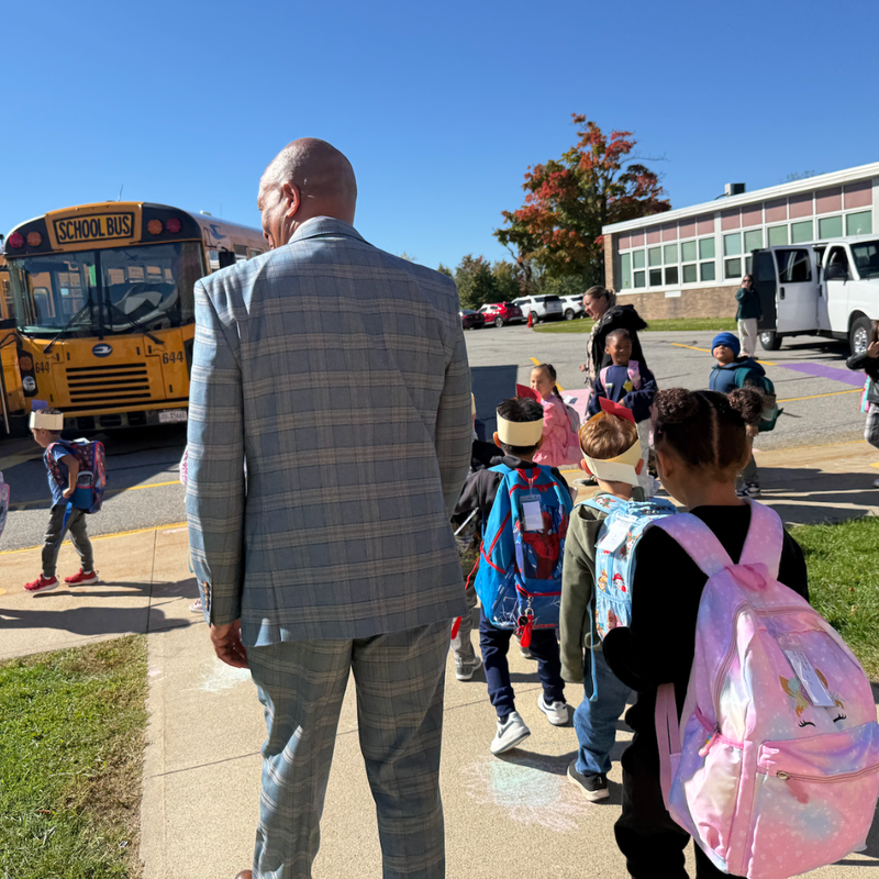 man walking students to school buses