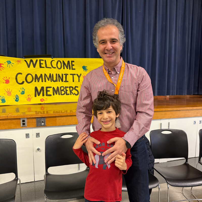man with a pink shirt stands with boy with a red shirt