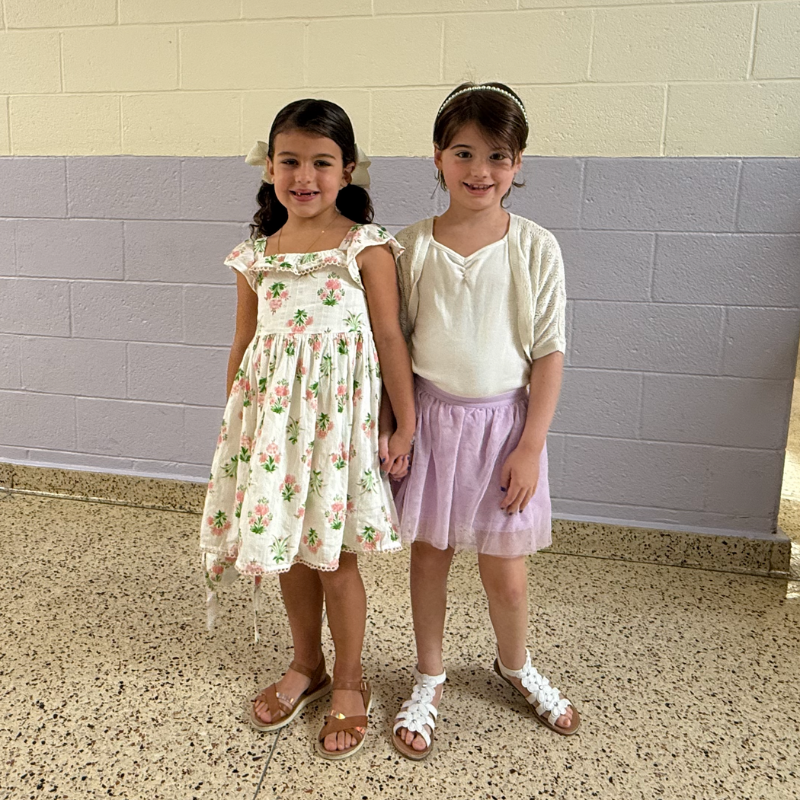 two student wearing dresses standing in a purple and white hallway
