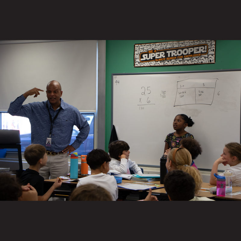 man with a blue shirt standing next to a white board