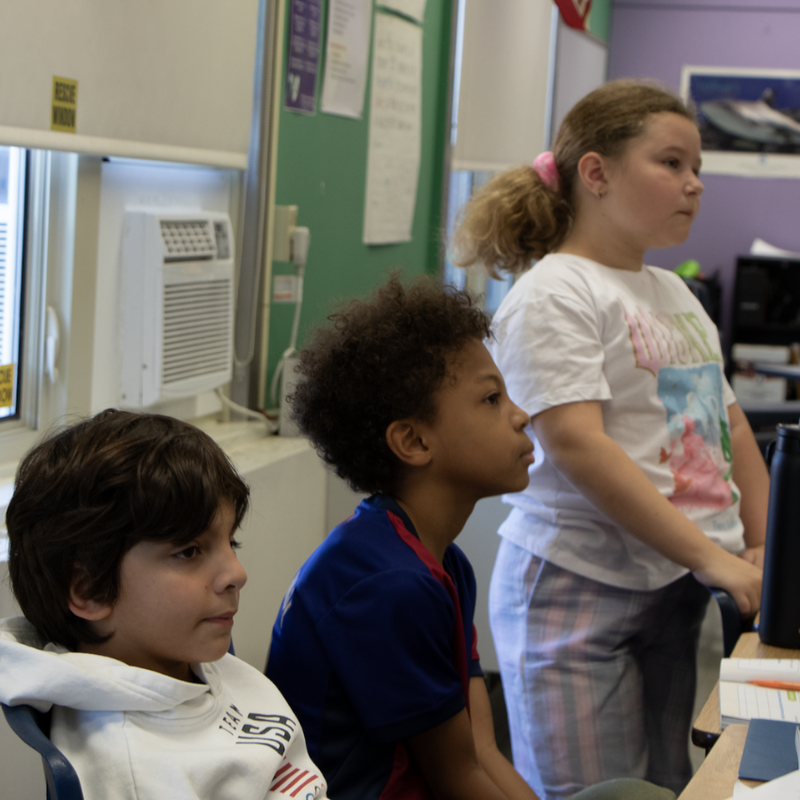 three students looking a teacher