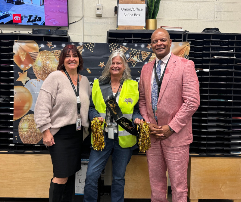 man with pink suit, woman with green vest and woman with brown shirt