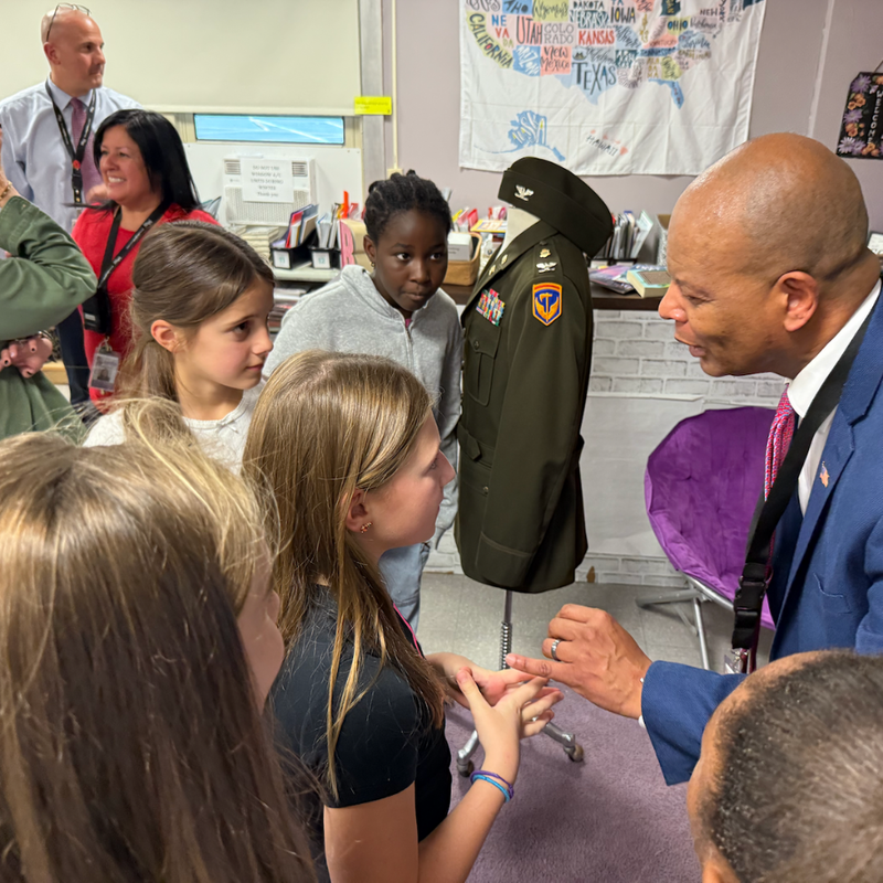 man in blue suit listening to students