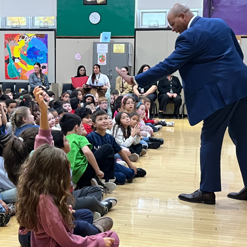 man with a blue suit giving student high fice