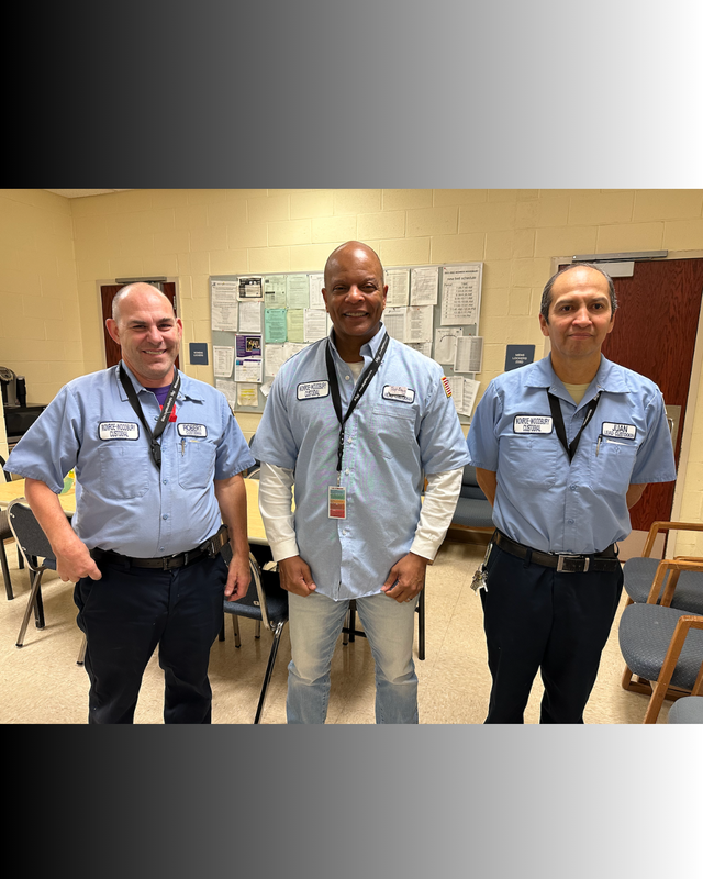 three men standing with blue shirts