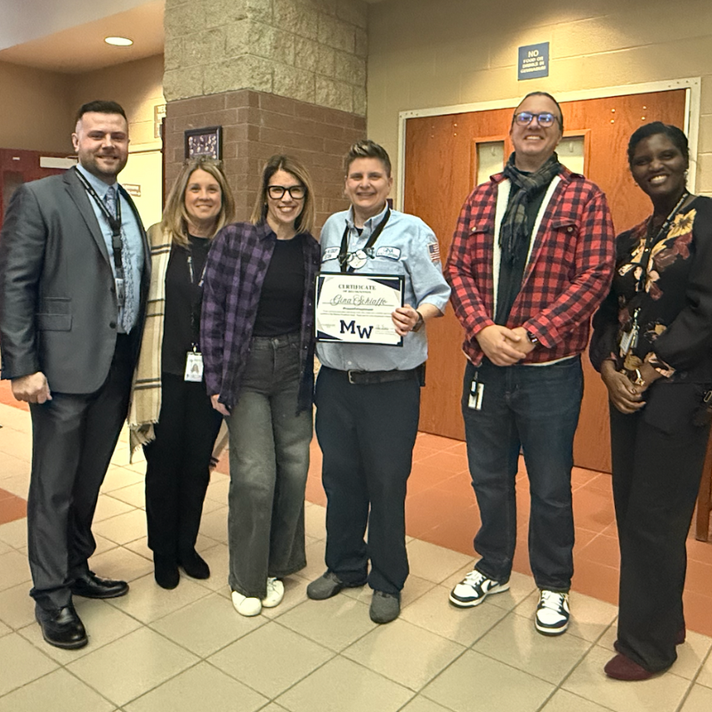 people standing holding a certificate in brown hallway 