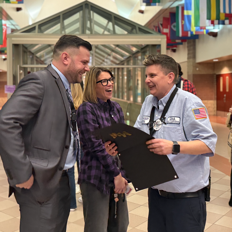 three people laughing holding a certificate