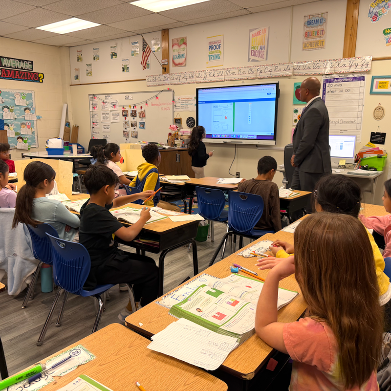 man standing in classroom with smart board and students