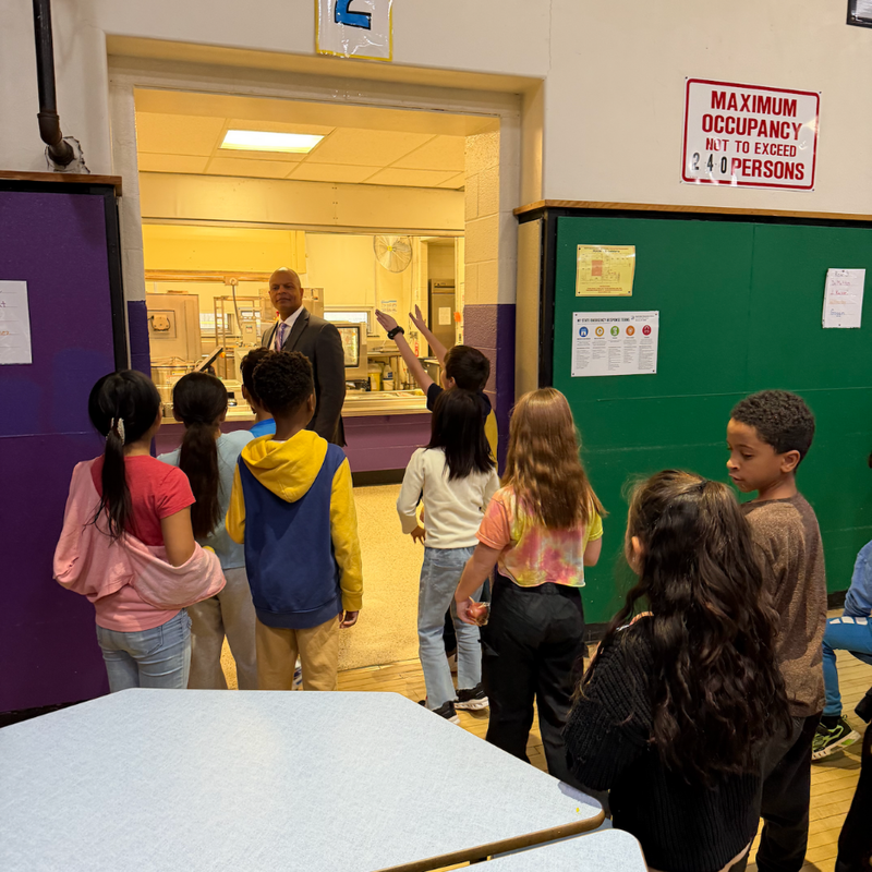 man in a suit standing next green wall in cafeteria