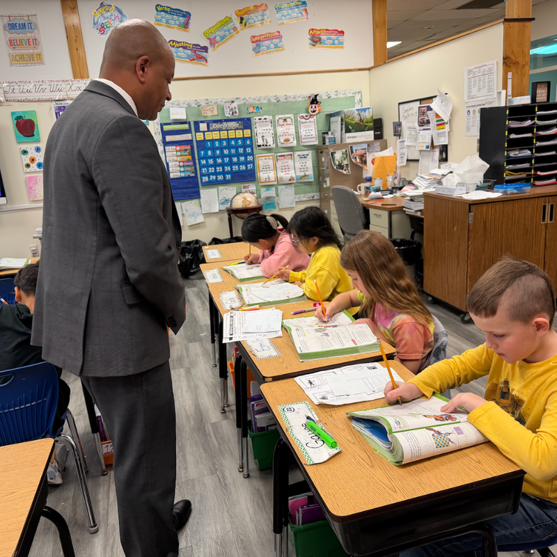 man standing next to students reading at a desk