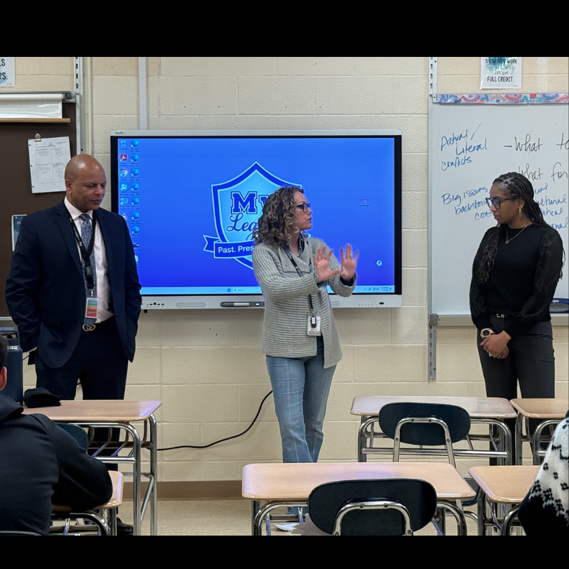 three people standing in front of a smart board