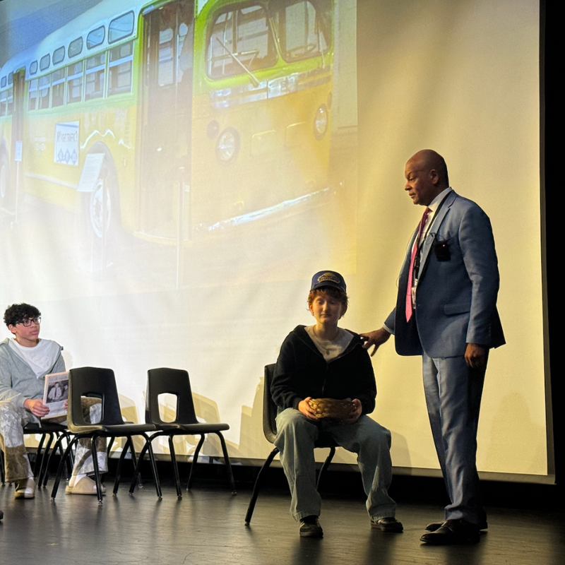 students and man standing on stage
