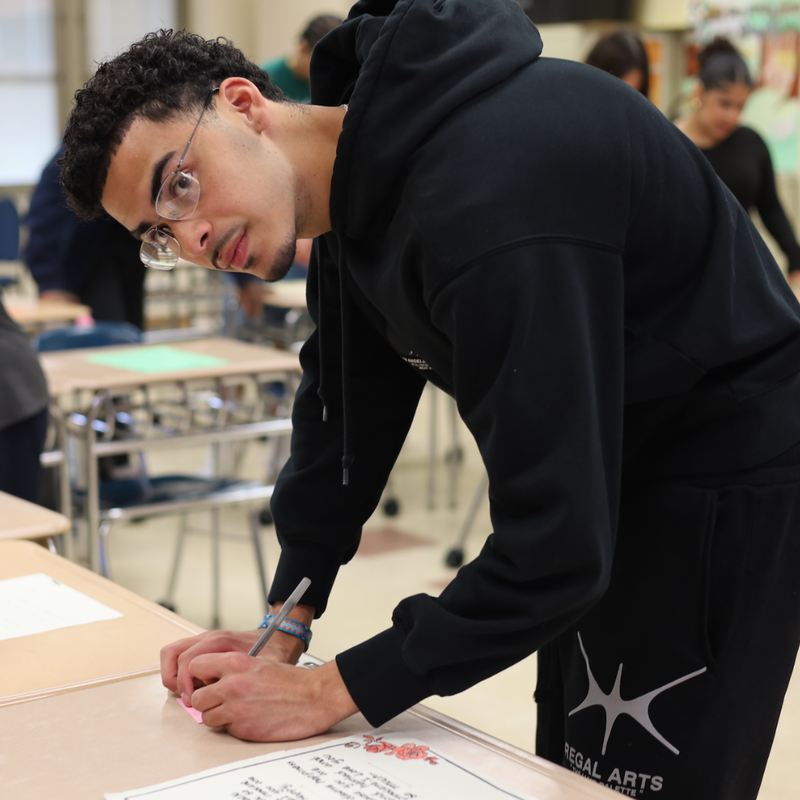 student wearing all black standing at a table 