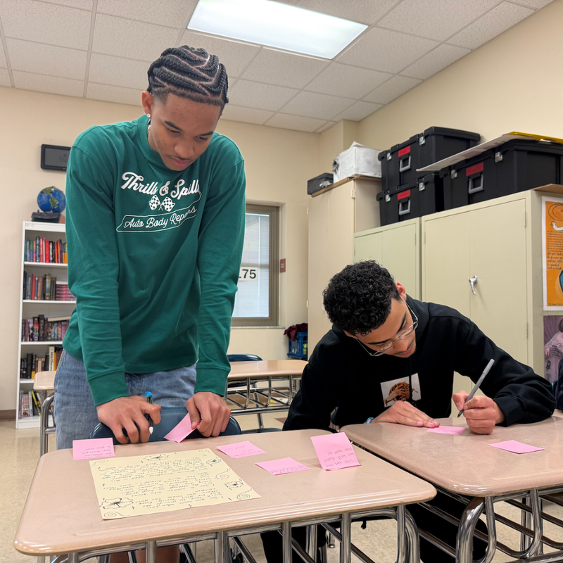two students writing at a table