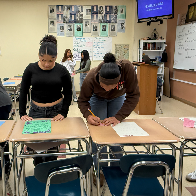 two students writing at a table 
