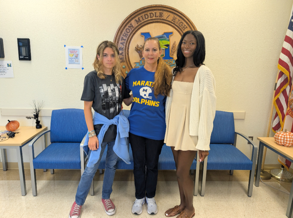 students and principal in front of school logo