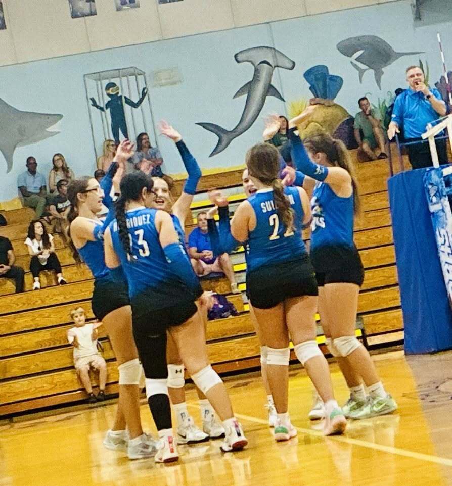 Volleyball team high fives on the court after winning the Conch Cup