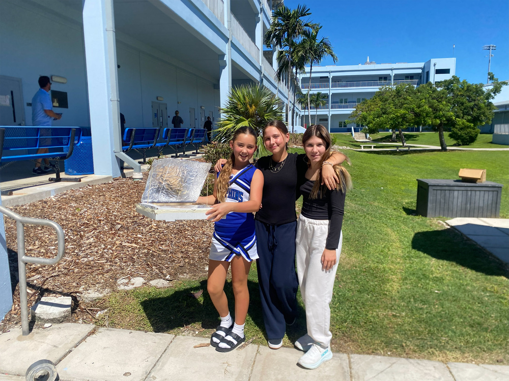three girls holding up a solar oven