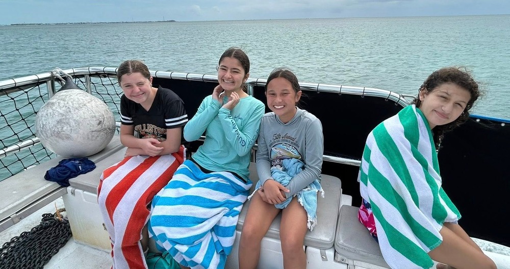 Four girls on a boat learning about coral reefs