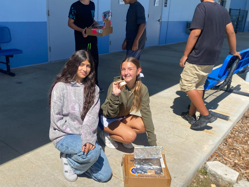 students posing with solar ovens and s'mores
