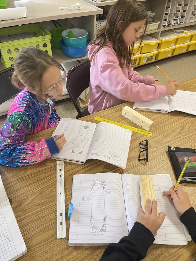 Students working on derby car designs in journal