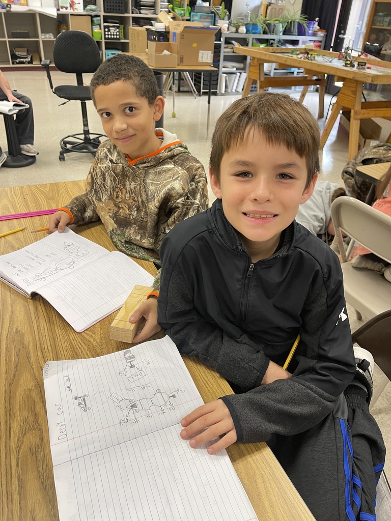 Students working on derby car designs in journal