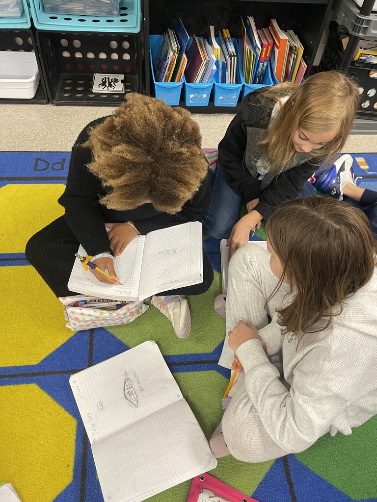 Students working on derby car designs in journal