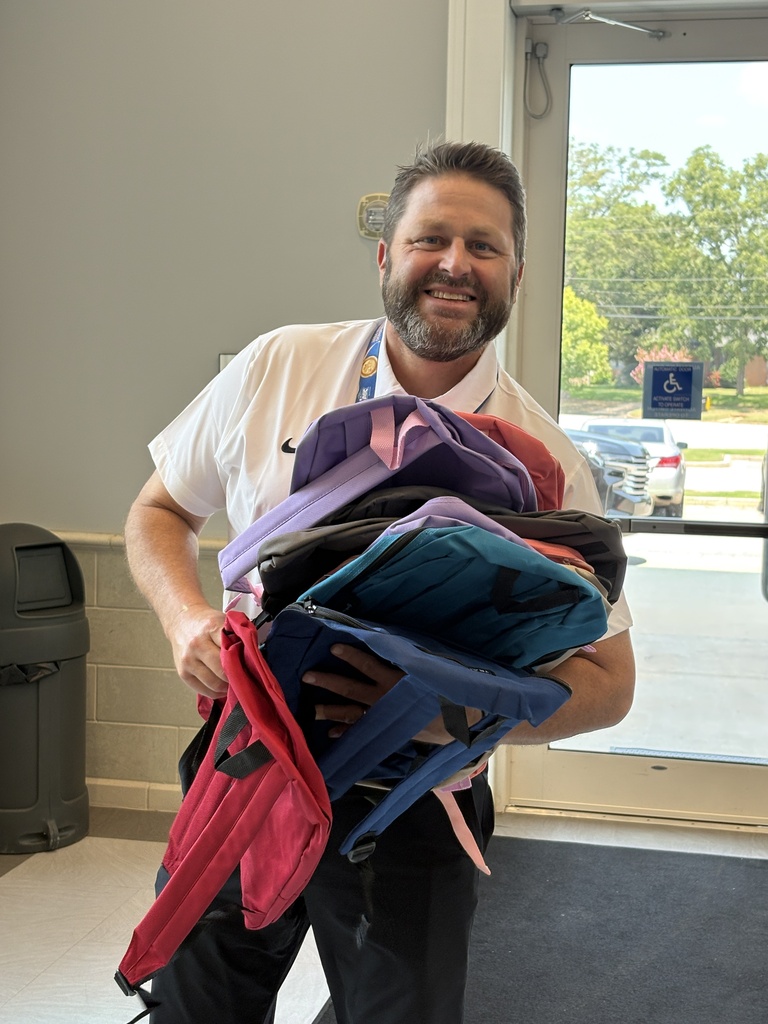 Dr. Finch holding a stack of backpacks