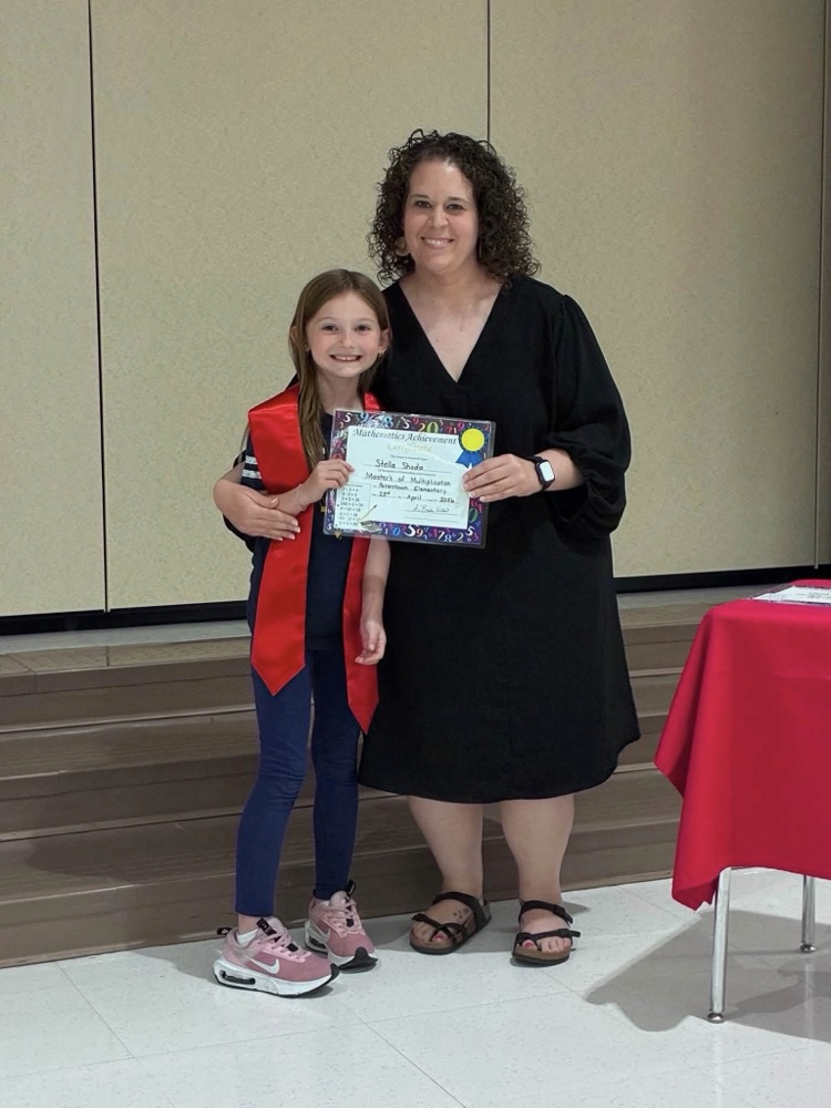 student in blue pants with Miss Wills putting on a red 