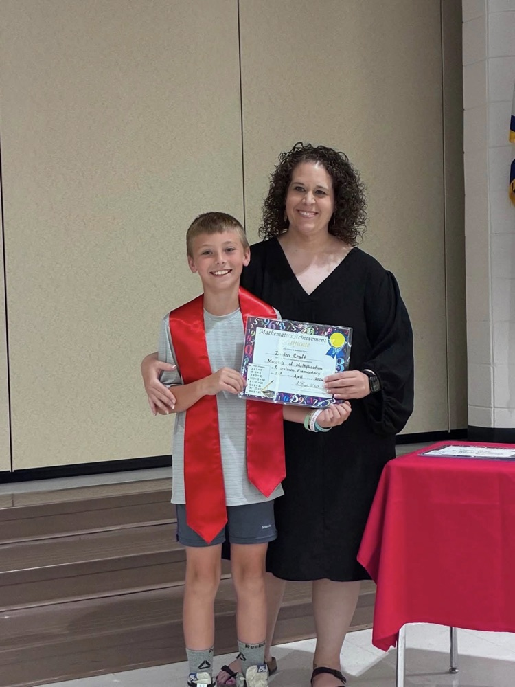 student and gray shirt and shorts with Miss Wills putting on a red sash