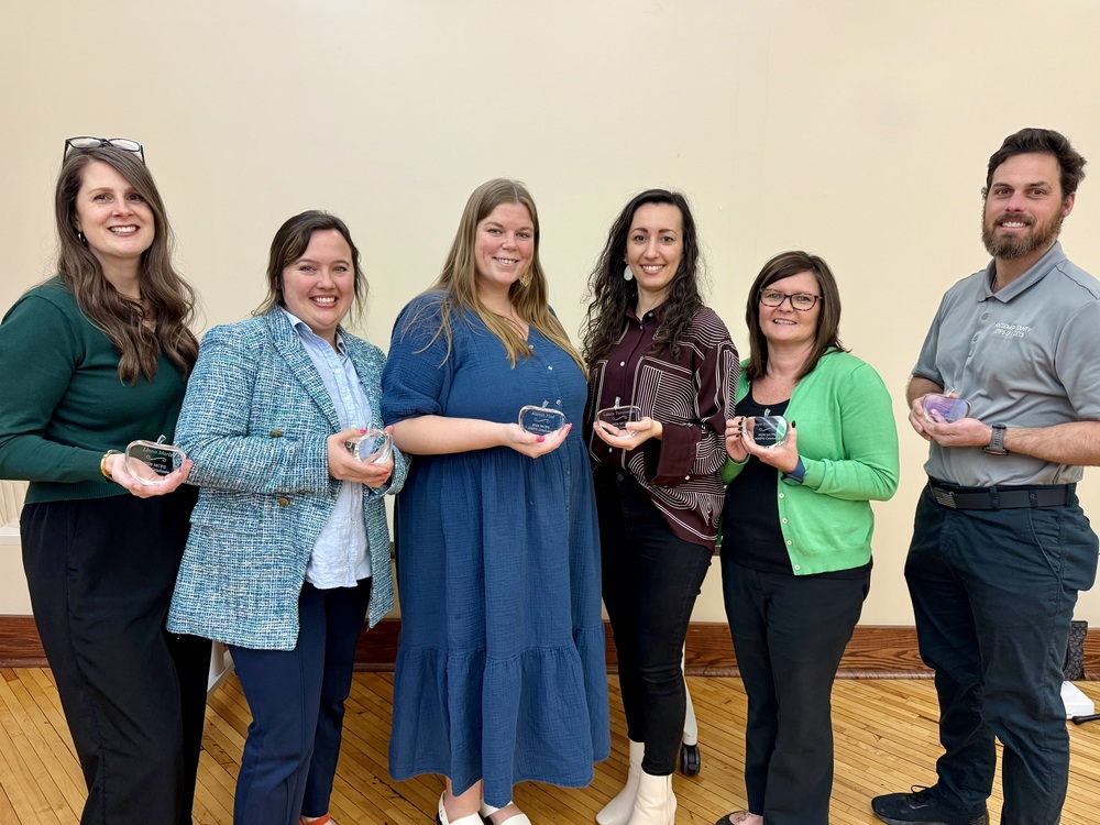 Six people standing with glass awards for a photo