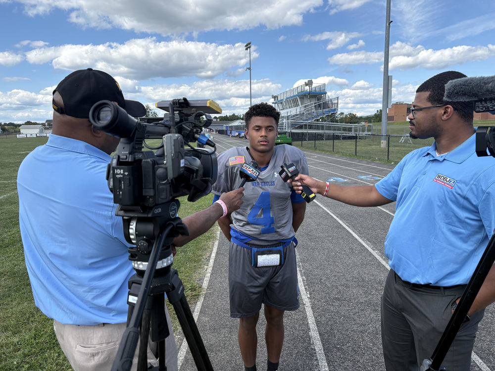 AHS football player being interviewed by two news stations