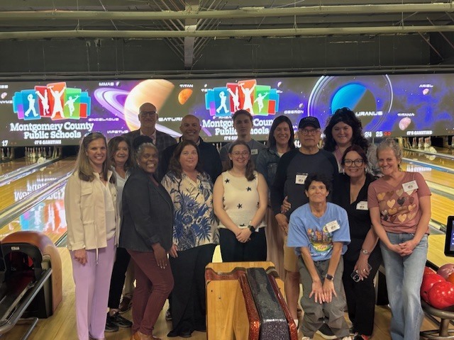 A large group of people smiling together at a bowling alley for a WE R.E.A.C.H. event titled "Bowling For Belonging."
