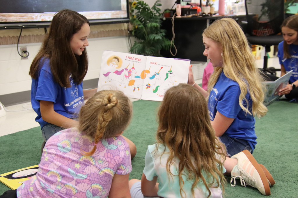 Two AMS students reading a story to two kindergarteners