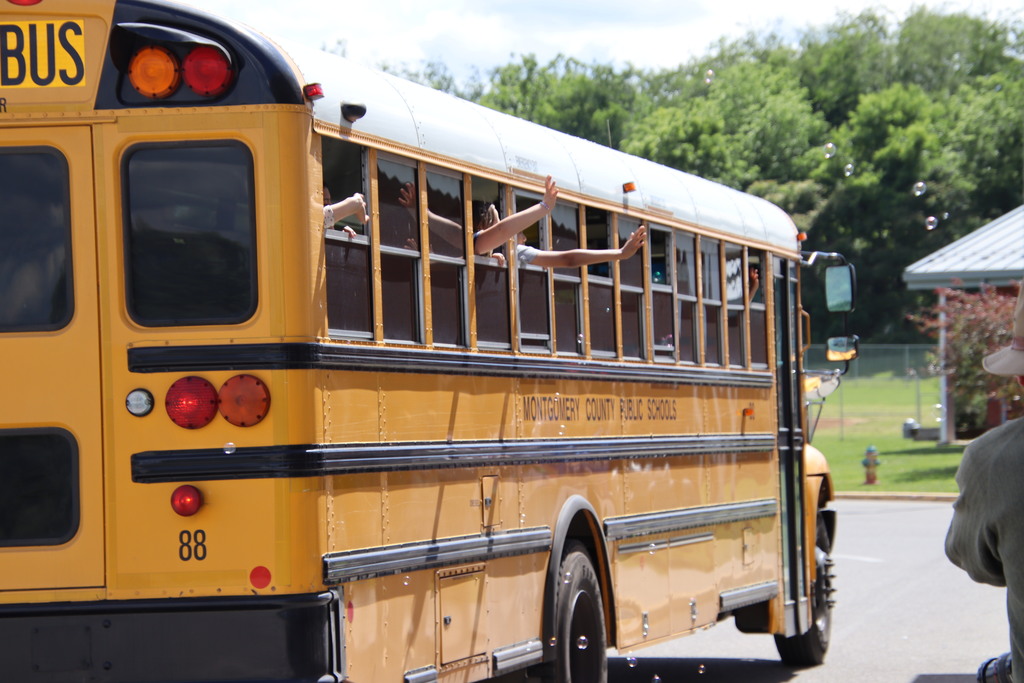 Students waving outside of a bus