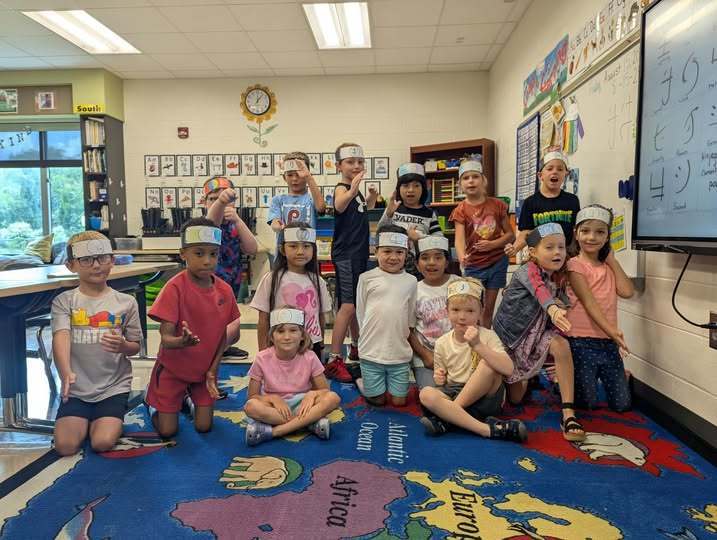 Students smiling wearing the ninja hats they made