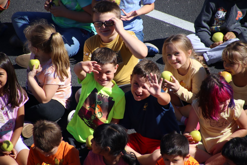 Two student waving at a camera