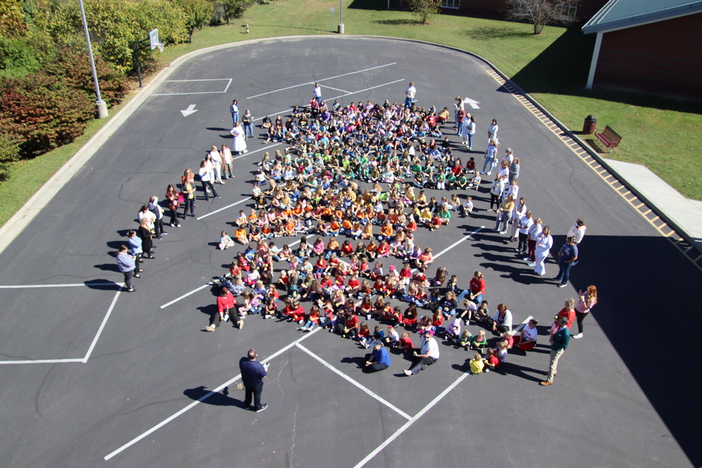 wide shot of the entire EMES student body sitting on pavement 