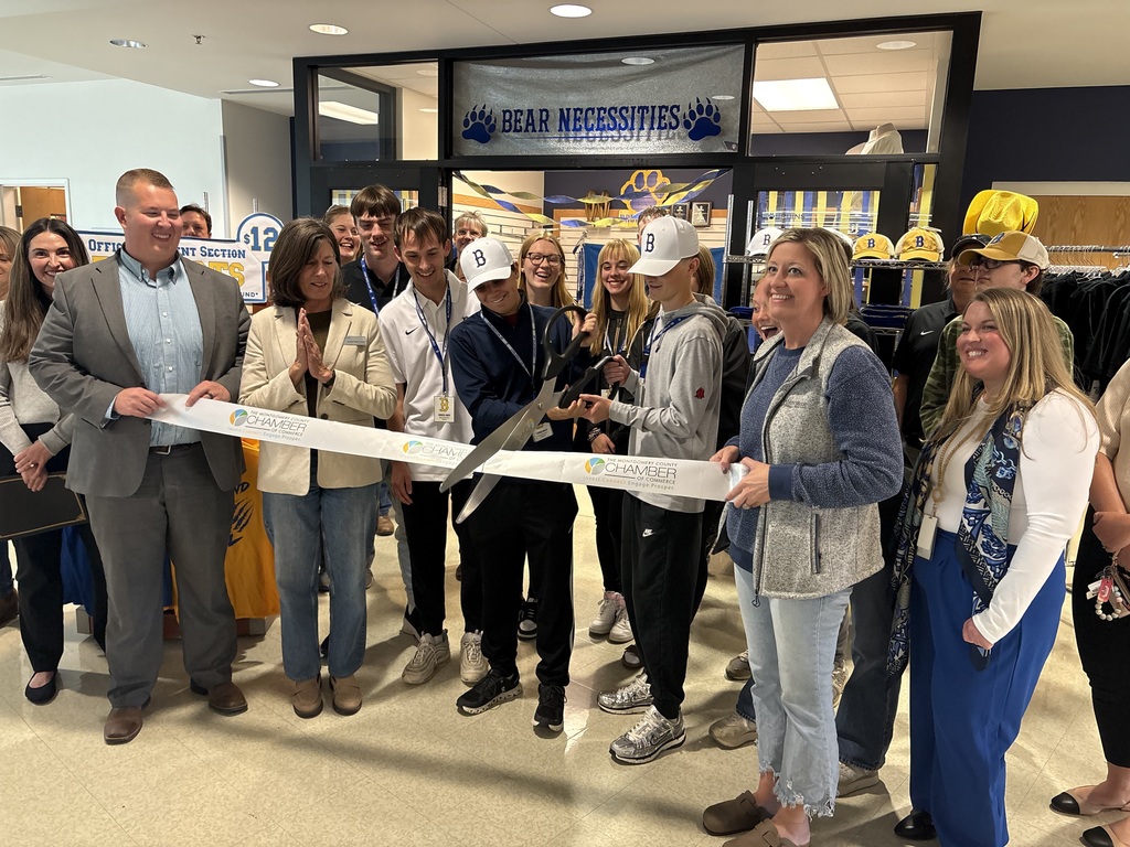 Members of the Bear necessities team cutting a ribbon to signify the grand opening of the school store
