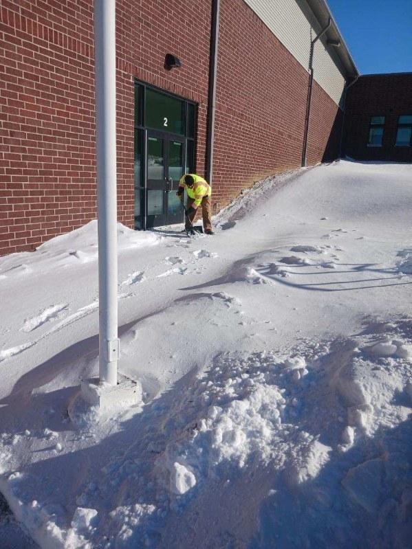 a man shoveling snow in front of a school