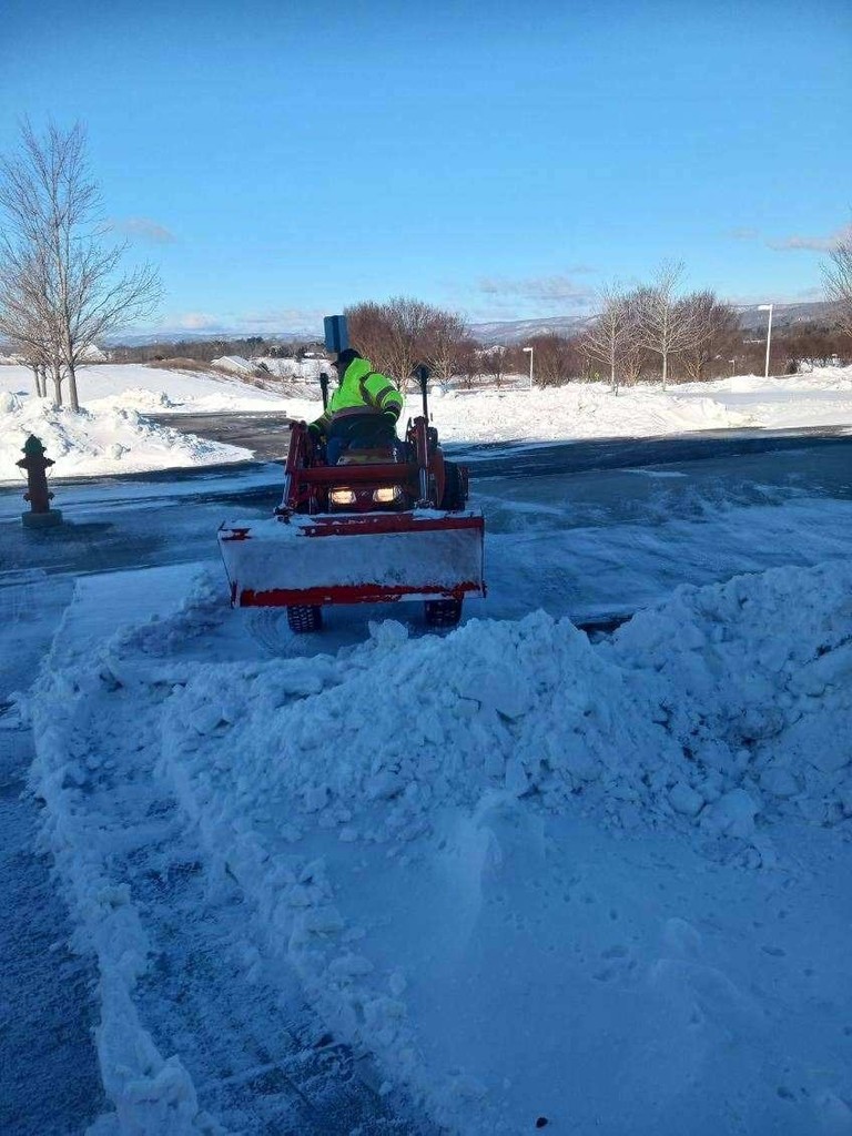 A man driving a tractor moving snow