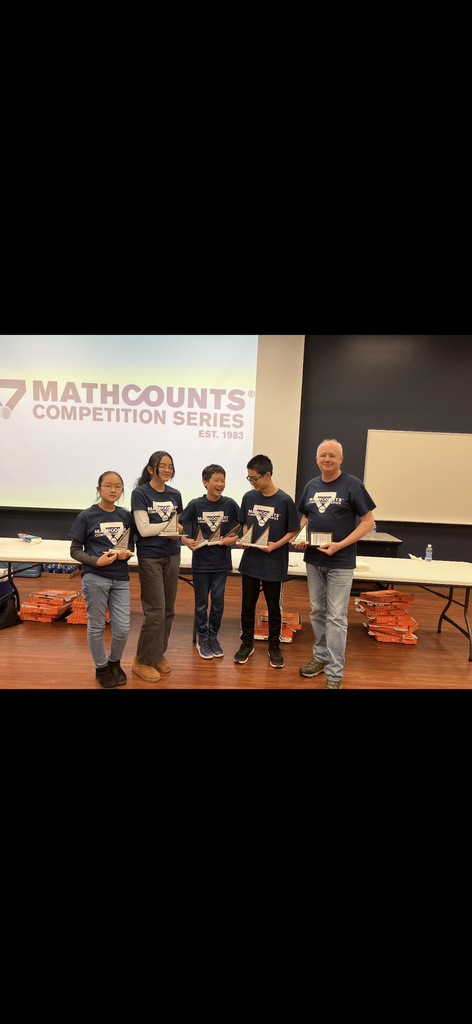 Four members of the Math Counts team standing beside their coach holding trophies
