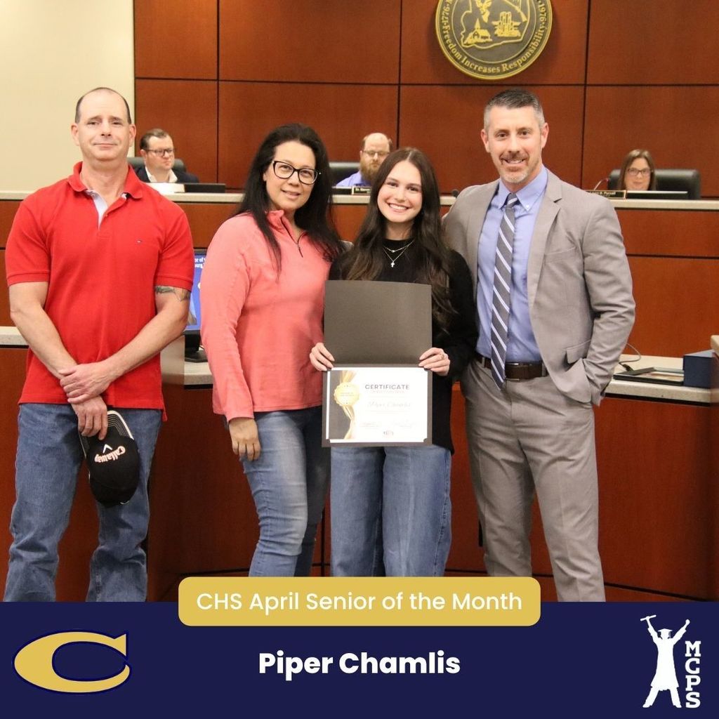 A formal group photo titled "CHS April Senior of the Month" featuring Piper Chamlis. Piper is smiling in the center, holding a certificate and wearing a black top and jeans. She is standing with two family members and a man in a grey suit and striped tie. They are in a boardroom in front of a wooden dais. A large "C" mascot and the MCPS logo are at the bottom.
