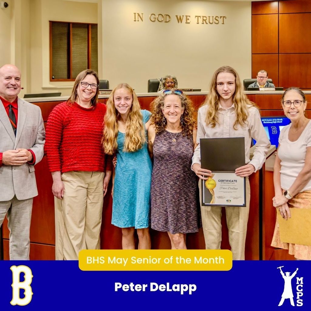 Peter DeLapp holds his BHS May Senior of the Month certificate, standing with a group of five adults and students in a formal room