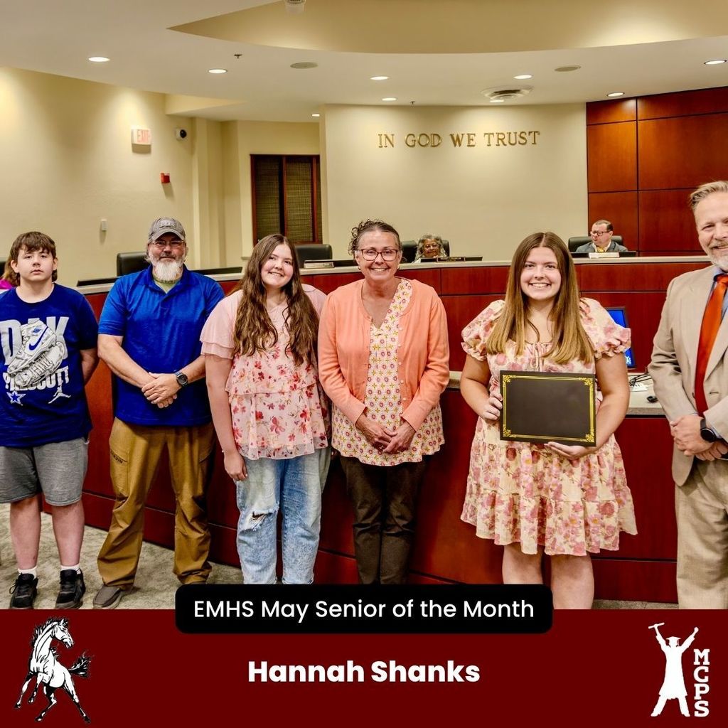 Hannah Shanks holds her EMHS May Senior of the Month certificate, standing with family and an official in a formal setting.