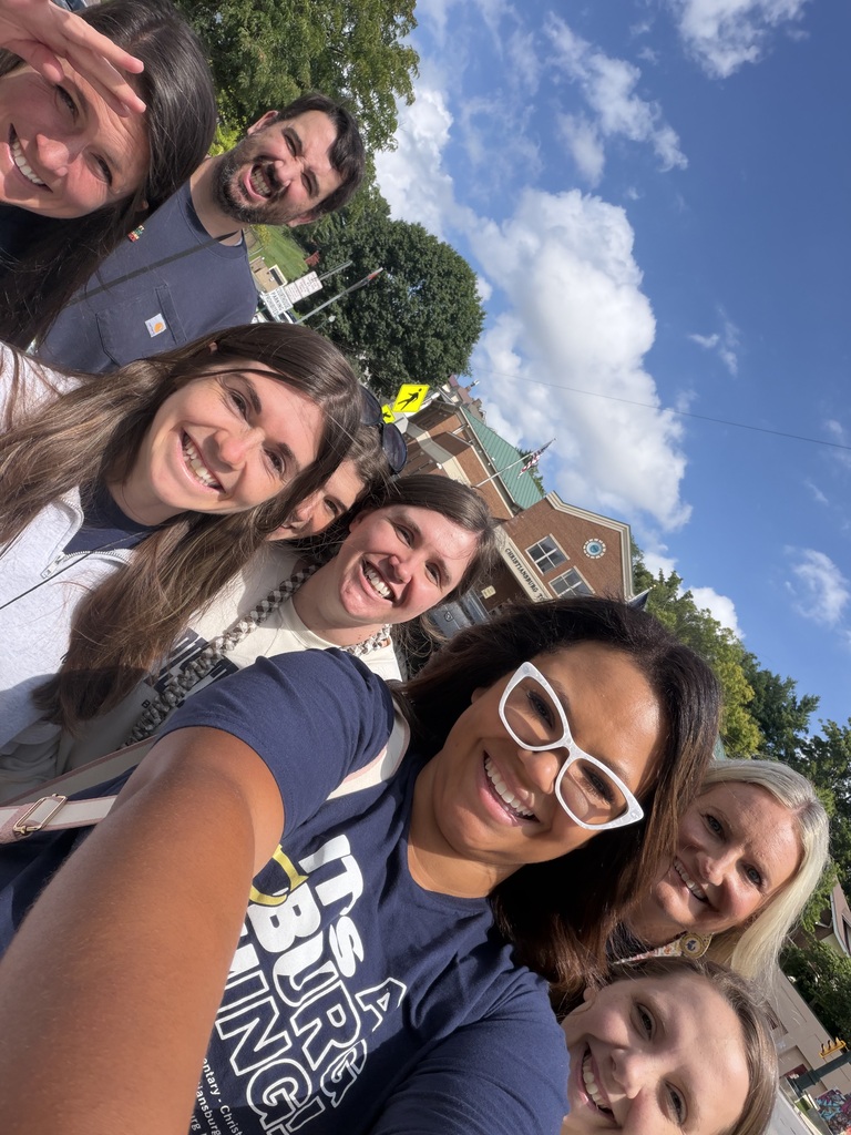 A group of smiling CES staff members gather for an outdoor selfie near downtown Christiansburg under a bright blue sky.