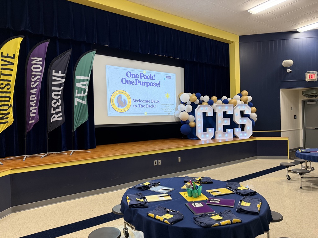 The CES cafeteria is decorated for the staff welcome-back event with house banners, navy-and-gold balloons, illuminated CES letters, and a screen displaying “One Pack! One Purpose!”